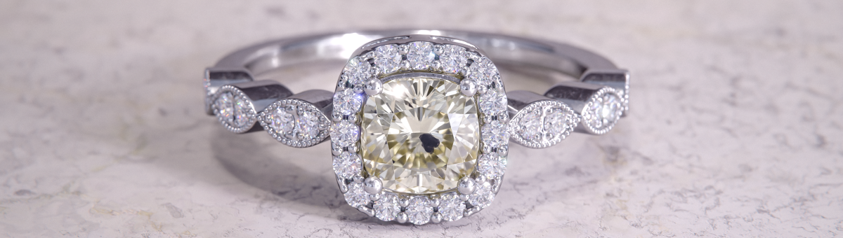 Cushion cut yellow diamond halo ring by Lurozzia, with a natural "beauty spot", crafted in white gold with South African diamonds and marquise shoulders. Featuring a J-color, I1 clarity center stone with a natural inclusion. Designed by Roelien Riekert and rendered by Ruan Riekert of Riekert Render Co for the De Beers Tirisano Mmogo campaign.